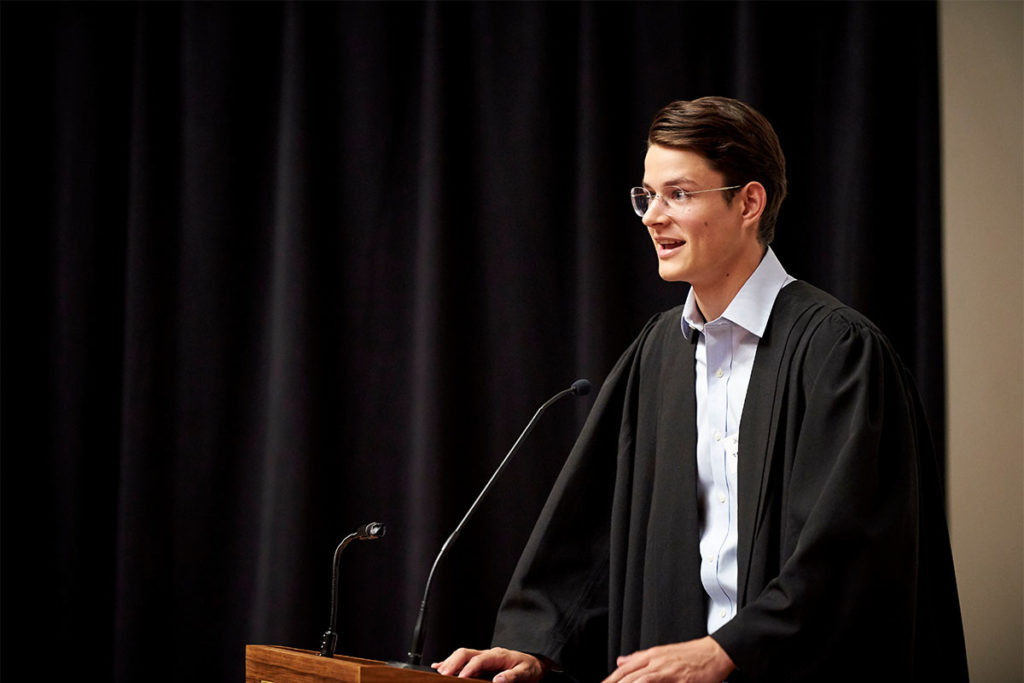 Tom giving a speech at a lectern