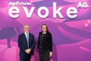 AgriFutures Australia Chair, The Hon Mick Veitch and Managing Director, Brianna Casey AM standing in front of a bright pink media wall with a white sign above them that read "AgriFutures evokeAG".